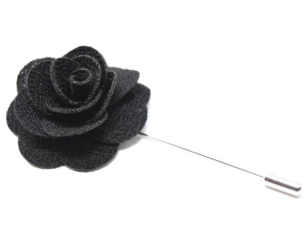 A large black flower lapel pin.