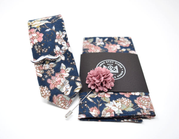 This box comes with a matching dusty rose and navy floral pattern tie and pocket square, rose lapel pin, and brushed silver moustache tie bar.